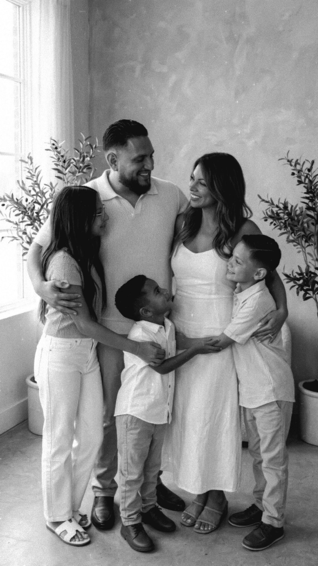 The AME Family — mom, dad, their daughter, and their two boys standing close together in a black-and-white portrait